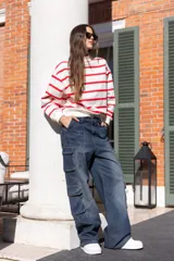 Buzo blanco con rayas horizontales rojas, de corte holgado y cuello redondo.