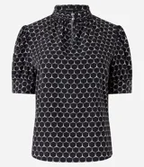 Blusa de crepé con estampado geométrico de hexágonos, cuello alto con abertura y botones, y mangas cortas abullonadas con pliegues.