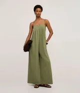 Mono de mujer color verde oliva, de pierna ancha y tiro alto, con escote recto y fruncidos en el busto. Los breteles son finos y trenzados en dos tonos.