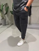 Jean de corte slouchy en color negro con efecto gastado. Presenta un diseño de tiro medio, ajuste holgado en la cadera y piernas que se estrechan hacia el tobillo.