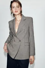 Blazer de corte entallado con estampado de pata de gallo, cuello solapa de muesca, manga larga con hombreras y cierre frontal cruzado con botones dorados. Cuenta con bolsillos con solapa en el delantero y forro interior a contraste.