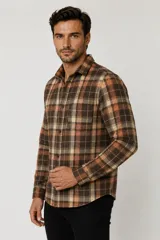 Sobrecamisa de franela a cuadros en tonos marrón, tostado, naranja y blanco, de manga larga con cierre frontal de botones y un bolsillo en el pecho.
