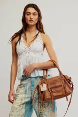 Cartera de cuero verde militar con acabado gastado, cuerpo blando, asas de mano, bolsillos frontales con cierre y tiras colgantes.