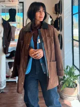 Campera de ecocuero color chocolate, con corte amplio y relajado. Presenta cuello camisero, cierre frontal con botones metálicos y bolsillos frontales de gran tamaño.