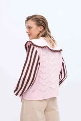 Buzo de punto color rosado con mangas largas a rayas marrones y rosadas. Presenta un doble cuello XL en color rosado con borde marrón y terminación de rulo, además de un cuerpo con detalles de calados y puntos tejidos.