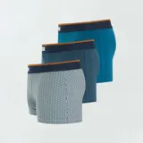 Pack de tres boxers de algodón elastizado, uno liso color celeste, uno con estampado geométrico azul oscuro sobre celeste y otro con estampado geométrico celeste sobre blanco. Todos tienen cintura elástica con logo de la marca.