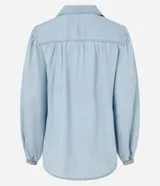 Camisa de denim liviano confeccionada en lyocell, con cuello camisero, cierre frontal de botones y mangas largas abullonadas con puños elásticos ajustados.