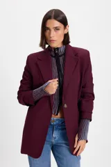 Blazer de corte sastrero en color bordó, con solapas clásicas, cierre frontal de un botón y mangas largas.