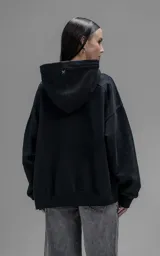 Hoodie oversize de corte crop, color negro, confeccionado en frisa gamuzada de algodón. Presenta capucha forrada, mangas largas con puños elásticos y bolsillo tipo canguro frontal.