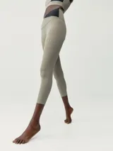 Legging capri de entrenamiento color beige claro, con cintura cruzada bicolor (beige y negro) y logo pequeño en la parte inferior de la pierna.