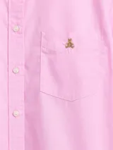 Camisa de manga larga color celeste, con cuello clásico, cierre frontal de botones, bolsillo en el pecho con detalle bordado y dobladillo redondeado.