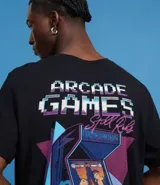 Remera negra de algodón con estampa en la espalda de una máquina de videojuegos arcade con un carpincho jugando. Incluye la frase 'Arcade Games Still Rocks' y detalles de puntaje.