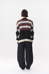 Buzo de tejido de punto con diseño geométrico y combinación de colores en contraste. Presenta cuello redondo, mangas largas y corte oversized.