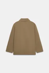 Chaqueta de corte recto y estilo camisero en color beige, con cuello solapa, manga larga y cierre frontal con botones. Presenta dos bolsillos delanteros de plastrón.