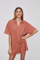 Mono corto color naranja, con cuello camisero, mangas cortas y cierre frontal con botones.