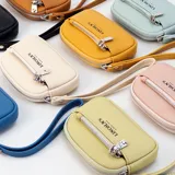 Monedero de mano con diseño rectangular y textura granulada, marca Lincoln's. Cuenta con cierre perimetral, bolsillo frontal con cierre y correa de muñeca integrada.