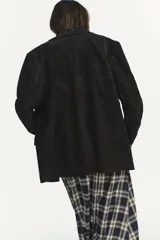 Blazer de piel de ante color marrón con efecto envejecido, solapas con muesca, cierre frontal de dos botones y bolsillos con solapa en el delantero. Cuenta con forro interior y costuras marcadas.