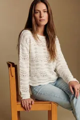 Sweater de punto calado con diseño de ondas horizontales, cuello redondo y mangas largas. Presenta un corte oversize y acabado en color blanco.