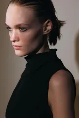 Vestido midi negro sin mangas, con cuello subido y detalle de drapeado en el delantero. Cierre en la espalda con cremallera oculta.