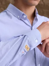 Camisa de manga larga con cuello button down, cierre frontal con botones y bolsillo en el pecho. Presenta un diseño de microestampado sutil en tono azul claro.