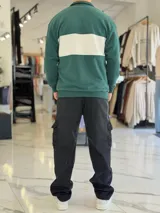 Hoodie de corte clásico con medio cierre y cuello alto, en color marrón con una franja horizontal blanca en el pecho que incluye el logo estampado en negro. Presenta además un pequeño bordado en el hombro izquierdo y puños y cintura elastizados de rib.
