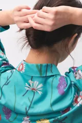Pijama de satén turquesa con estampado floral multicolor, compuesto por una camisa de manga larga con botones y cuello camisero, y pantalón largo a juego.