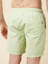 Short de baño tipo volley de color verde claro, con cintura elástica y cordón ajustable. Cuenta con un diseño liso y minimalista.