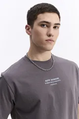 Remera de manga corta color gris oscuro, con escote redondo y fit regular. Presenta un estampado frontal con el texto "new season designed and produced by mistral".