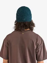Gorro tipo beanie de tejido de punto con textura acanalada y efecto moteado multicolor. Presenta una etiqueta cuadrada con el logo de la marca en el frente.