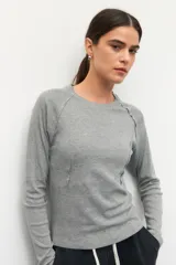 Remera de manga larga color blanco, confeccionada en algodón, con cuello redondo y diseño de costuras decorativas externas que realzan la silueta.
