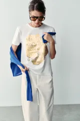 Camiseta blanca de manga corta y cuello redondo, con detalle de estampa central metalizada de efecto texturizado y diseño regular fit.