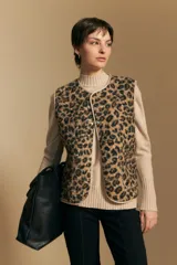 Chaleco de textura afelpada con estampado animal print, cuello redondo y cierre frontal con botones a presión. Cuenta con bolsillos laterales y ribetes al tono.