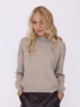 Sweater de punto color beige con cuello alto y detalle de strass en el cuello.