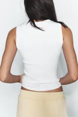 Top musculosa de punto acanalado color blanco, con cuello redondo.