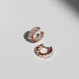 Par de aros tipo argolla oro rosa con cristales blancos en la superficie exterior e interior.