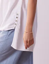 Blusa blanca sin mangas de lino, marca Zac & Rachel. Cuello con solapa, escote en V y abertura central con botones. Delantera con bolsillos aplicados. Laterales con botones aplicados.