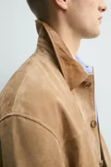 Chaqueta relaxed fit de piel con acabado serraje en color tostado, con cuello de solapa combinado a contraste, bolsillos de plastrón con solapa en la cadera y cierre frontal de botonadura.
