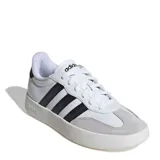 Championes Adidas modelo Barreda, de diseño retro con puntera estilo T-Toe. Presentan una combinación de cuero sintético blanco y detalles en gamuza gris claro, con las icónicas tres tiras laterales en color negro y suela cupsole de goma.