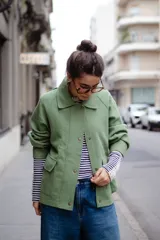 Chaqueta de lana afieltrada en color verde, con cuello clásico, cierre frontal con broches metálicos y bolsillos delanteros con solapa. Presenta un diseño de espalda amplia con apertura para mayor movimiento.