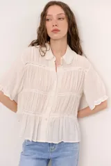 Camisa beige de manga corta con cuello camisero, detalles de encaje y cierre frontal con botones.