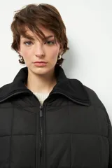 Campera marrón capitoneada de manga larga con cuello alto de tela, cierre frontal y bolsillos laterales con cierre.