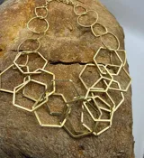 Collar dorado con cadena de eslabones circulares y colgantes de hexágonos geométricos.