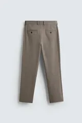 Pantalón chino de corte slim fit, confeccionado en tejido elástico. Presenta bolsillos frontales, bolsillos traseros de vivo con botón y cierre frontal con cremallera y botón.
