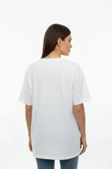 Remera de algodón de manga corta y cuello redondo, con diseño holgado y estampado frontal con motivos florales y texto.