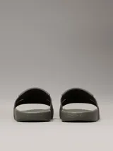 Ojotas tipo slide de color verde oliva, con doble tira superior de TPU con relieve y logotipo grabado. Cuentan con plantilla moldeada ergonómica con soporte para el arco plantar y suela de EVA.