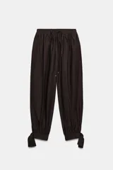 Pantalón de tiro medio con cintura elástica ajustable mediante cordones. Presenta un diseño de pernera abullonada con puños ajustables mediante lazos en los tobillos y bolsillos laterales ocultos en las costuras.