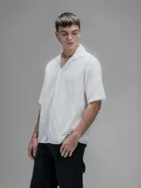 Camisa blanca de manga corta, con cuello abierto y calce oversize. Confeccionada en algodón bordado tipo broderie con diseño floral.