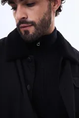 Campera negra con cuello de corderito sintético, cierre frontal con botones y bolsillos laterales. Diseño de corte recto y estructura resistente.