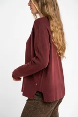 Sweater de tejido de punto color bordó, con cuello redondo, mangas largas y puños acanalados. Presenta un diseño de corte recto y textura suave.