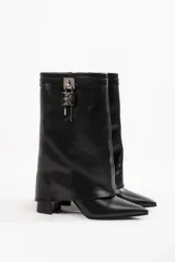 Bota de cuero color beige con punta fina, taco de 10cm y detalle de candado plateado en la caña.